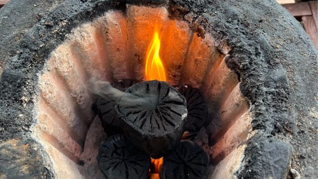 炭をさらに炎の上に置いている写真
