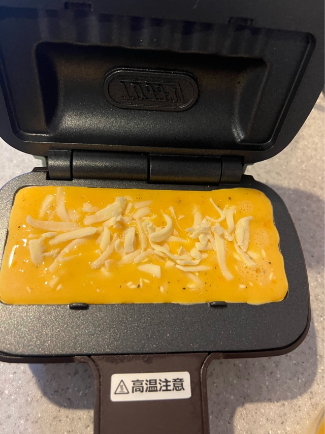 卵液の中にチーズを投入している写真