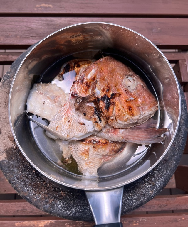水と昆布を入れた鍋に焼いた鯛のあらを入れて煮込んでいる写真