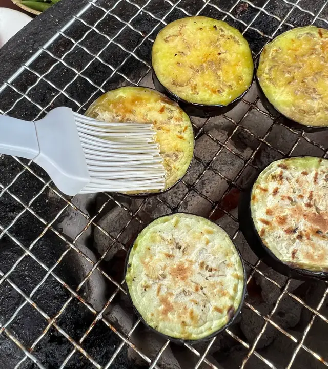 なすにオリーブオイルを塗って網焼きしている写真