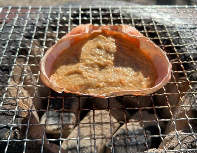 磯丸水産の蟹味噌甲羅焼きを七輪で焼く写真